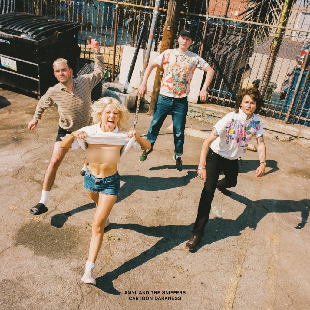 The cover of Amyl and the Sniffers' newest album, Cartoon Darkness. Each of the four band members is mid-run or jump and looking up toward the camera. The photo was taken on a very bright sunny day. There is a dumpster and a chain-link fence in the background. Amy Taylor is in front; she is sticking out her tongue and lifting up her shirt; her bare chest is blurred out.