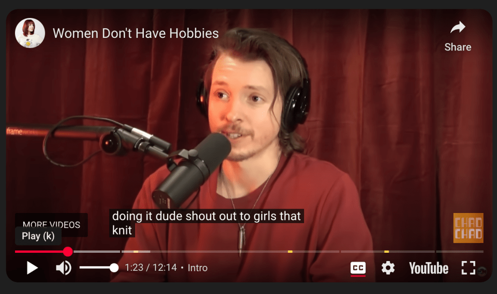 A screen shot of a Youtube video. The frame is of a man in a red shirt against a red curtain background talking into a podcast microphone. The closed caption reads "dude, shout out to girls that knit"